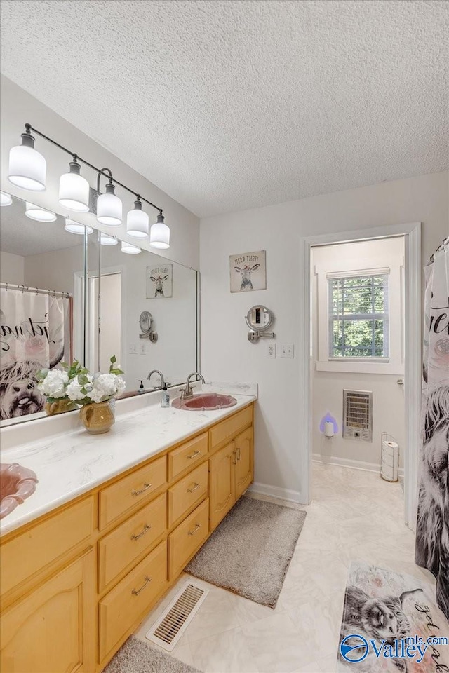 bathroom with vanity, a textured ceiling, and heating unit