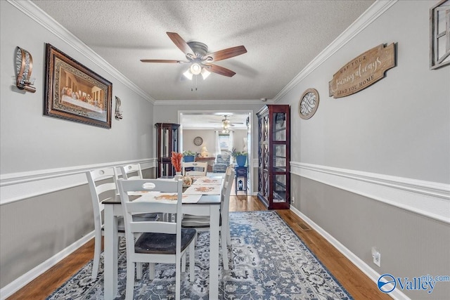 dining space featuring ceiling fan, ornamental molding, a textured ceiling, and dark hardwood / wood-style floors