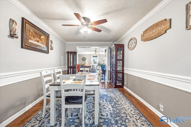 dining room featuring dark wood-type flooring, ceiling fan, a textured ceiling, and ornamental molding