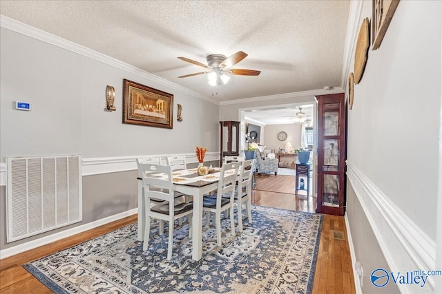 dining area featuring ornamental molding, hardwood / wood-style floors, a textured ceiling, and ceiling fan