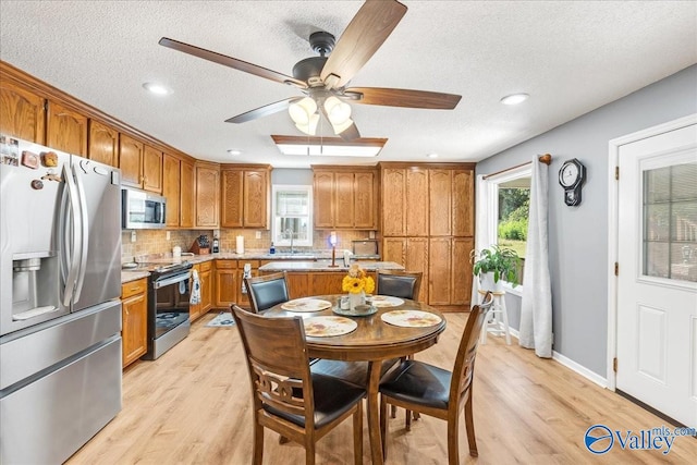 dining area featuring plenty of natural light, a textured ceiling, and light wood-type flooring