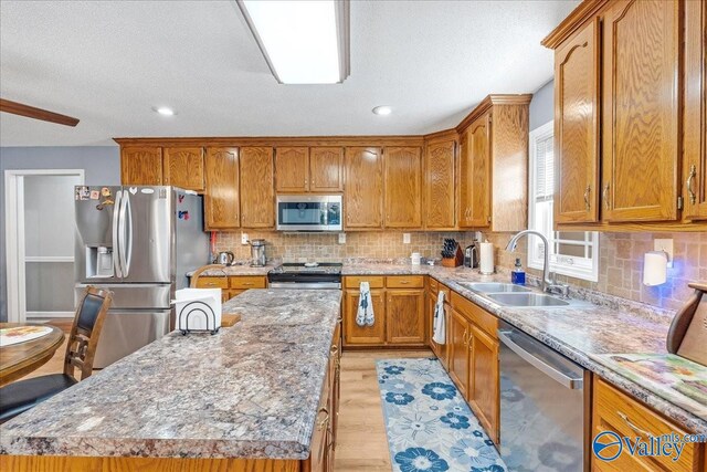 kitchen with appliances with stainless steel finishes, tasteful backsplash, sink, and light hardwood / wood-style floors