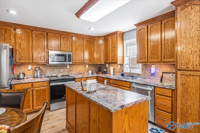 kitchen with sink, a center island, stainless steel appliances, decorative backsplash, and light hardwood / wood-style flooring