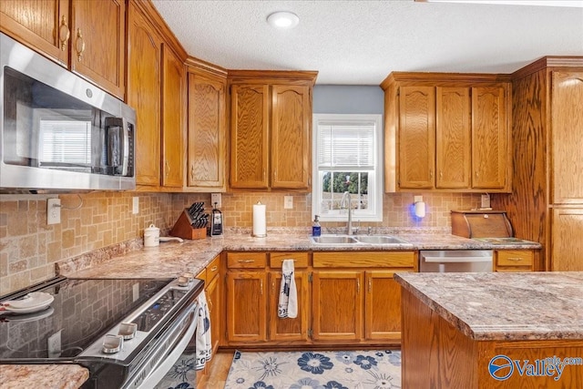 kitchen featuring a textured ceiling, stainless steel appliances, sink, and backsplash