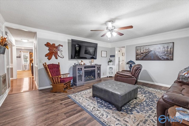 living room featuring a fireplace, wood-type flooring, crown molding, a textured ceiling, and ceiling fan