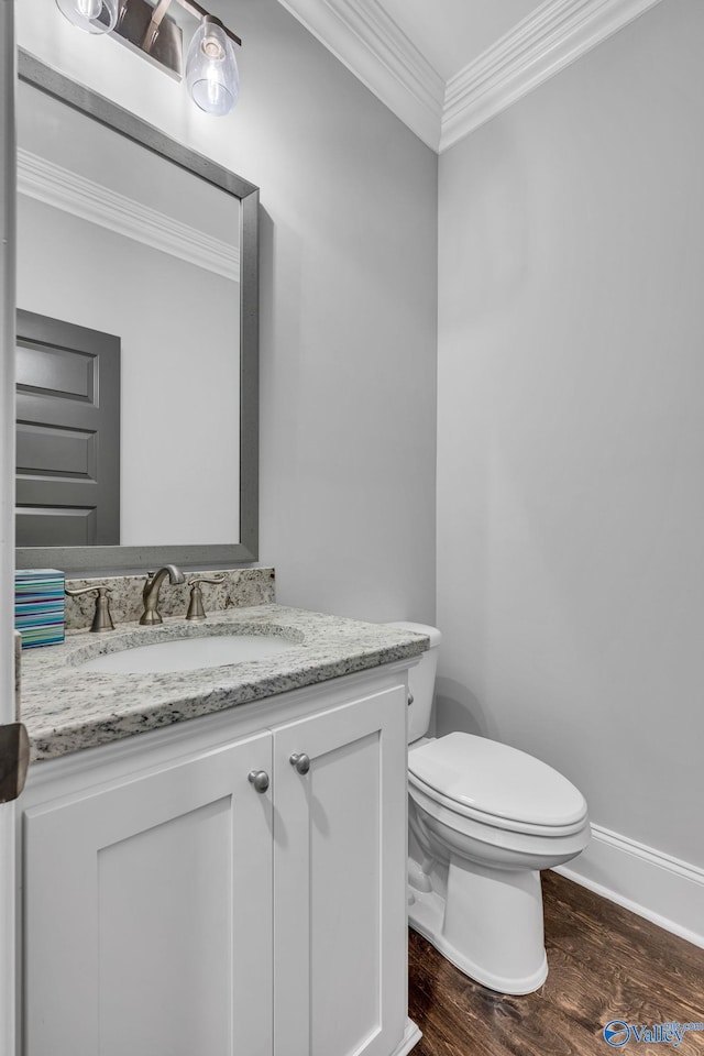 bathroom with vanity, toilet, ornamental molding, and hardwood / wood-style floors