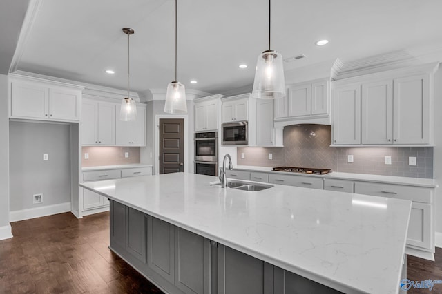 kitchen with appliances with stainless steel finishes, sink, a spacious island, white cabinetry, and decorative light fixtures