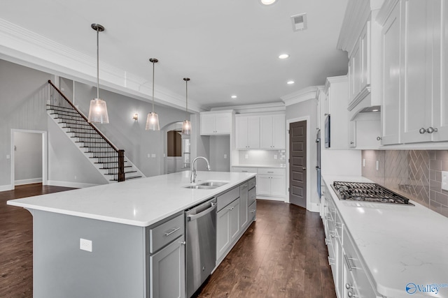 kitchen with appliances with stainless steel finishes, white cabinets, dark wood-type flooring, and an island with sink