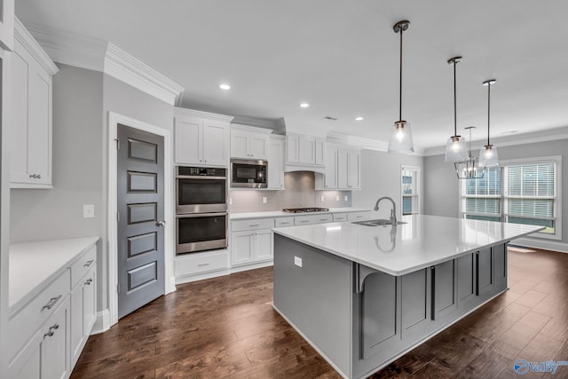 kitchen with dark wood-type flooring, hanging light fixtures, stainless steel appliances, sink, and white cabinetry