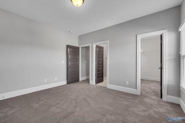 unfurnished bedroom featuring light carpet, a closet, and a spacious closet