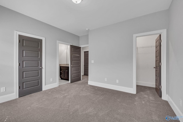 unfurnished bedroom featuring connected bathroom, carpet, a walk in closet, and a closet