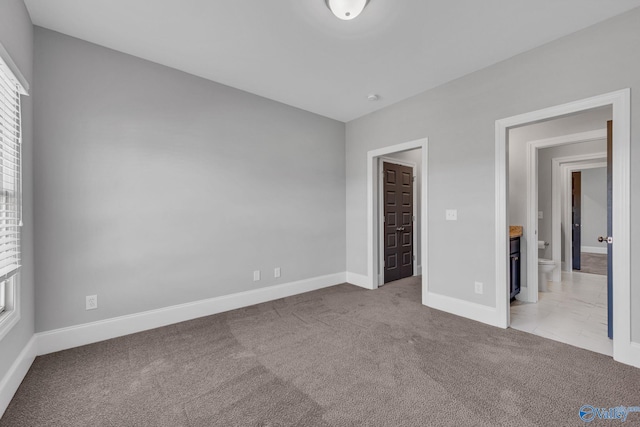 unfurnished bedroom with connected bathroom and light colored carpet