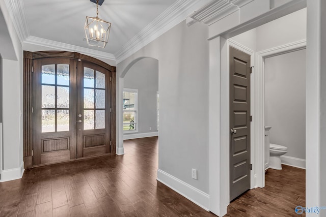 foyer entrance with ornamental molding, french doors, dark hardwood / wood-style floors, and a chandelier