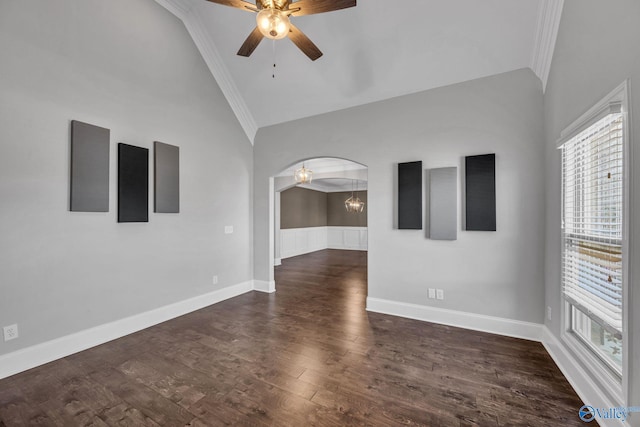 empty room featuring ornamental molding, dark wood-type flooring, vaulted ceiling, and ceiling fan