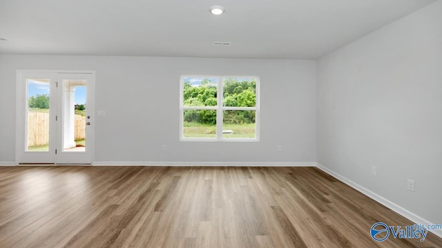 empty room with visible vents, wood finished floors, and baseboards