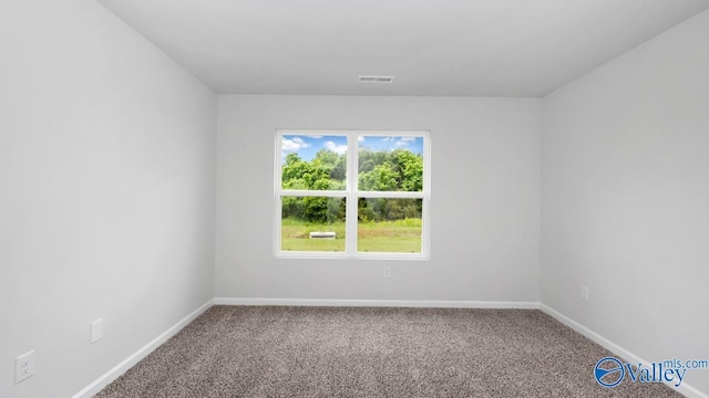 spare room with carpet flooring, visible vents, and baseboards