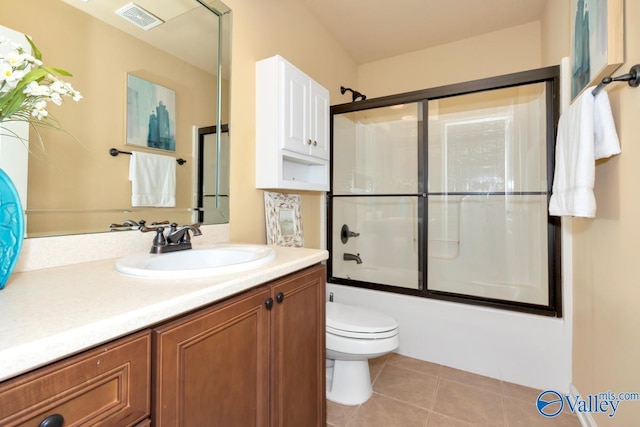 bathroom featuring visible vents, toilet, enclosed tub / shower combo, vanity, and tile patterned flooring