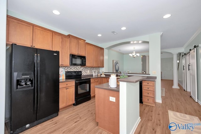 kitchen with decorative backsplash, dark countertops, a peninsula, crown molding, and black appliances