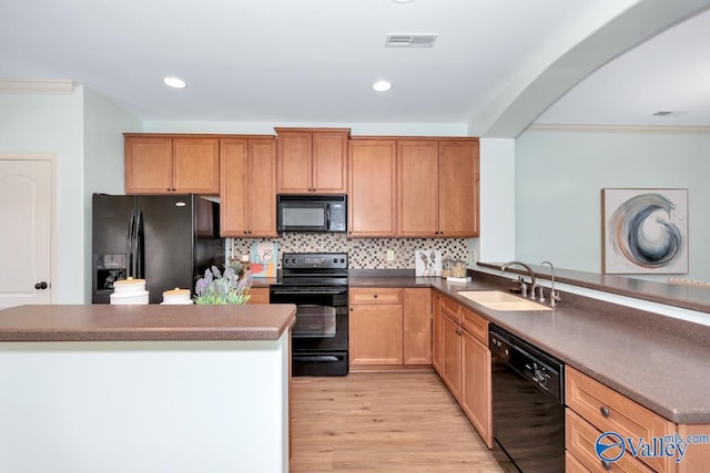 kitchen featuring tasteful backsplash, visible vents, light wood-type flooring, black appliances, and a sink