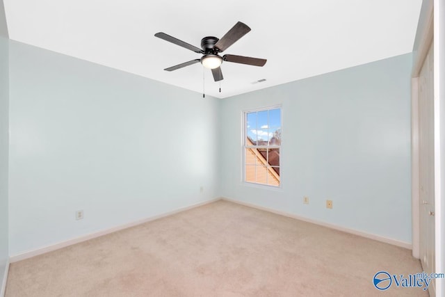 spare room with a ceiling fan, light carpet, visible vents, and baseboards