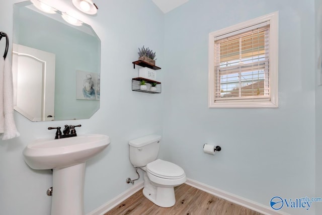 half bathroom with a sink, wood finished floors, toilet, and baseboards