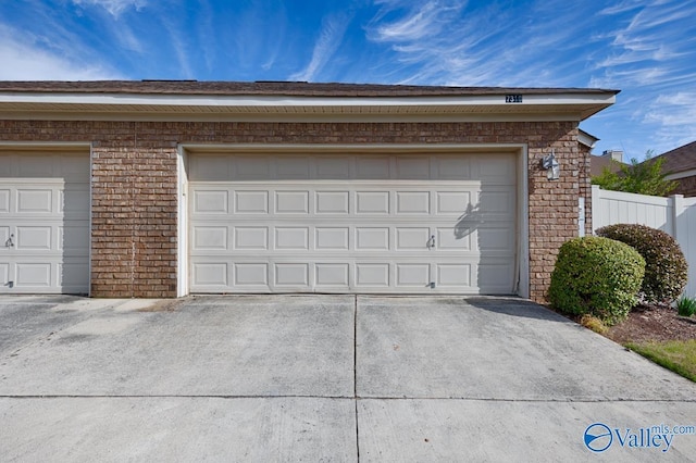 garage featuring driveway and fence