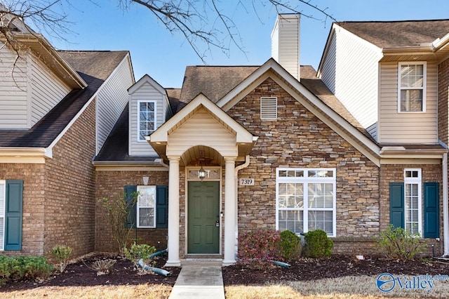 view of front of property with a chimney and brick siding