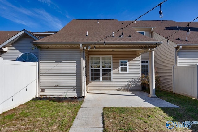 rear view of property featuring a yard, roof with shingles, fence, and a patio