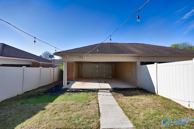 rear view of house featuring a fenced backyard, a lawn, and roof with shingles