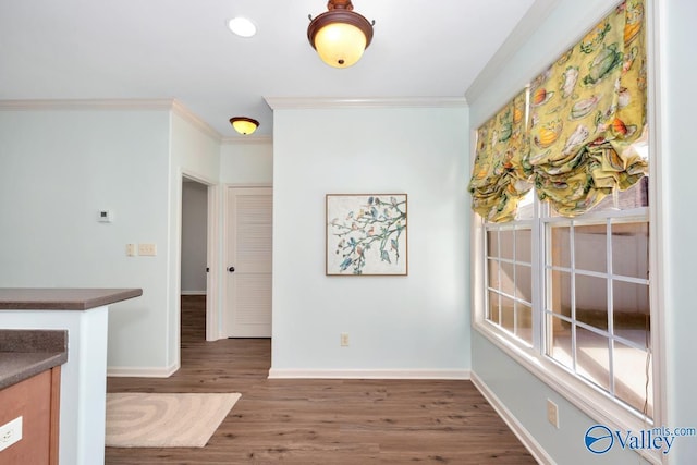 unfurnished dining area with ornamental molding, dark wood-style flooring, and baseboards