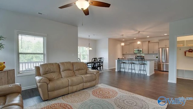 living room with dark hardwood / wood-style flooring, ceiling fan, and a wealth of natural light