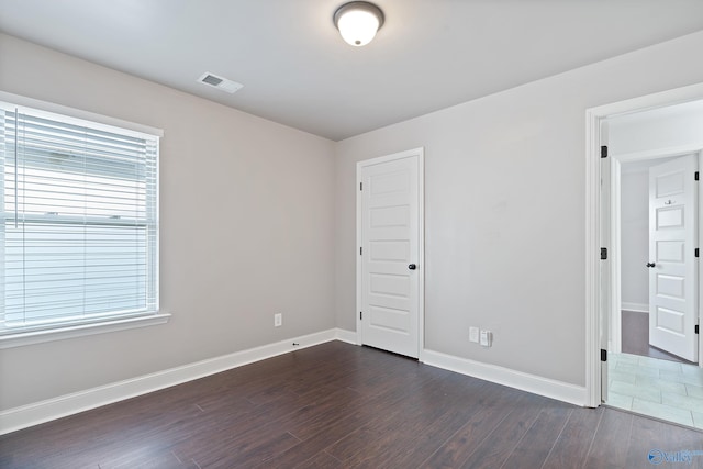 empty room with dark hardwood / wood-style floors and a healthy amount of sunlight