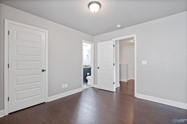 unfurnished bedroom with a closet, dark hardwood / wood-style floors, and ensuite bath