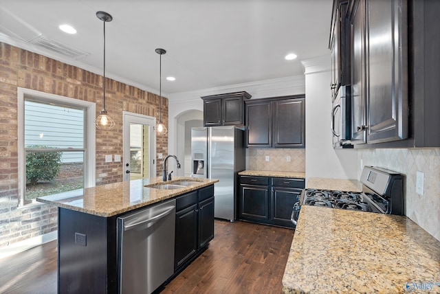 kitchen featuring stainless steel appliances, light stone counters, sink, an island with sink, and ornamental molding