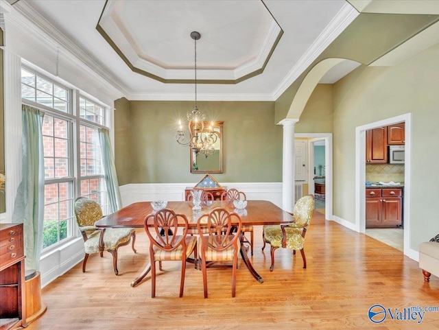 7515 Park Trace Ln SE, Owens Cross Roads, AL 35763 - dining area featuring a raised ceiling, light wood finished floors, arched walkways, ornate columns, and ornamental molding
