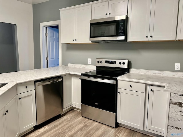 kitchen featuring light stone counters, white cabinets, light hardwood / wood-style floors, and appliances with stainless steel finishes