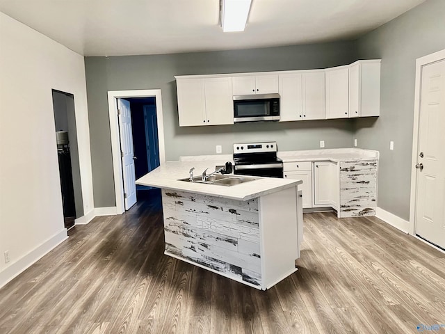 kitchen with electric range oven, white cabinetry, hardwood / wood-style flooring, and sink