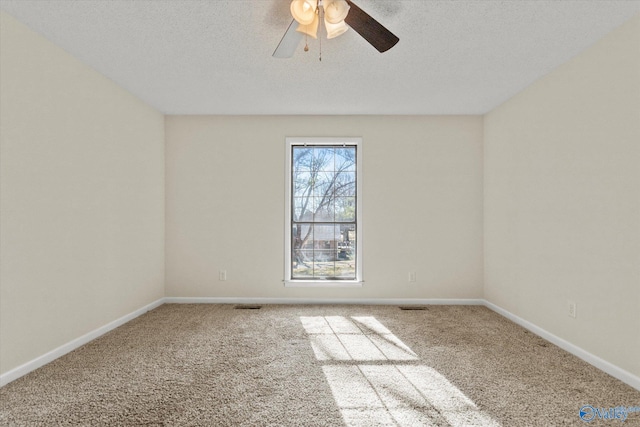 carpeted spare room featuring visible vents, baseboards, ceiling fan, and a textured ceiling