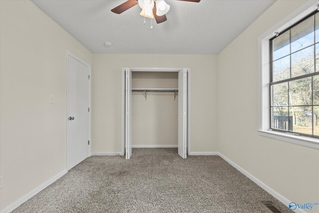 unfurnished bedroom with carpet floors, a textured ceiling, baseboards, and a closet