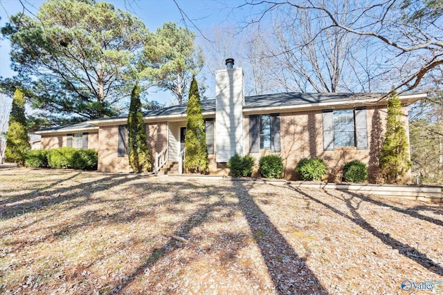 ranch-style house featuring brick siding and a chimney