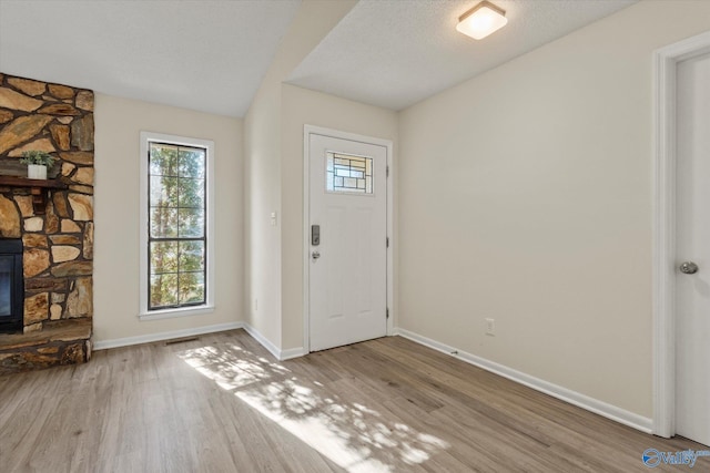 entrance foyer featuring a textured ceiling, baseboards, and wood finished floors