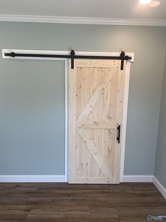 interior details with baseboards, wood finished floors, a barn door, and ornamental molding