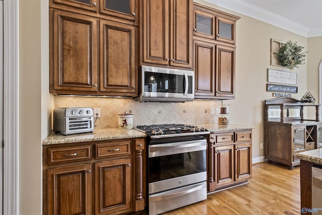 3602 Beason Cove Rd, Steele, AL 35987 - kitchen featuring appliances with stainless steel finishes, light wood-style floors, crown molding, decorative backsplash, and light stone counters