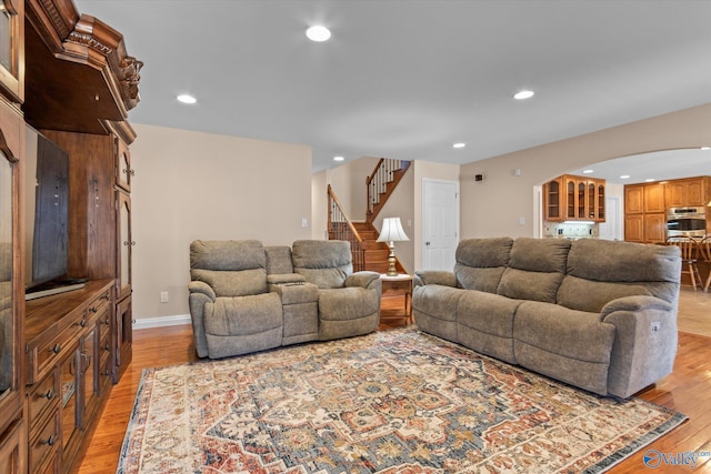 living room featuring recessed lighting, light wood-type flooring, and arched walkways