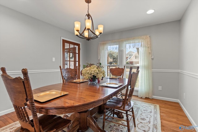 dining area featuring light wood-type flooring, baseboards, and a notable chandelier