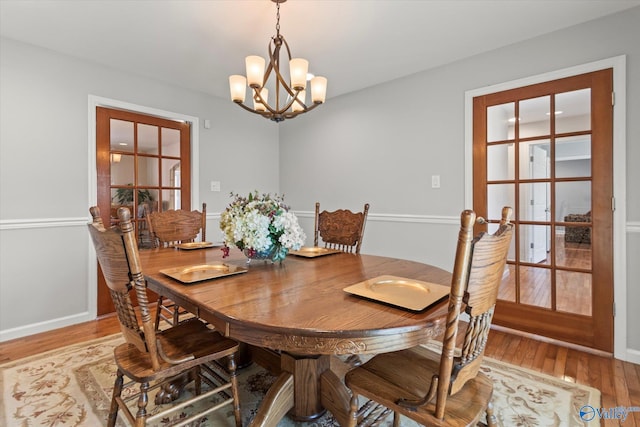 dining area with an inviting chandelier, light wood-style floors, and baseboards