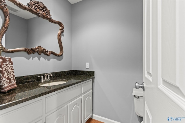bathroom with vanity, wood finished floors, visible vents, baseboards, and toilet