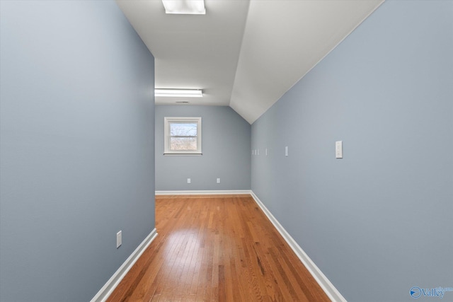 additional living space featuring lofted ceiling, light wood-style flooring, and baseboards