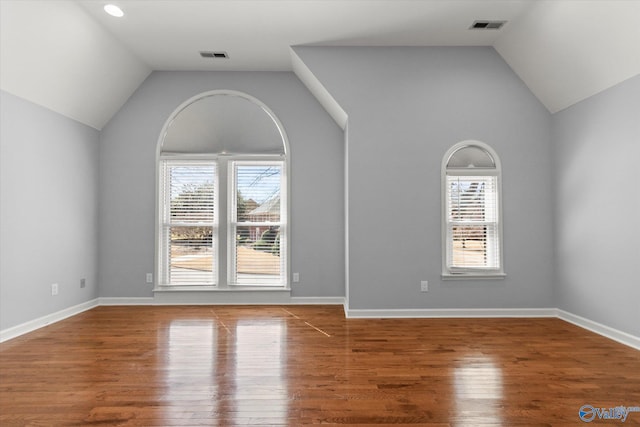 unfurnished room with a wealth of natural light, visible vents, lofted ceiling, and wood finished floors