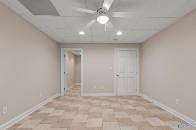 empty room with a drop ceiling, baseboards, and a ceiling fan